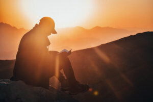 A Man Sitting on a Stone and Reading in the Sun